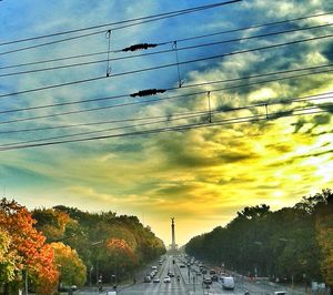 Cars on road against cloudy sky