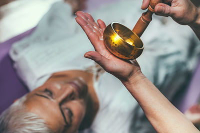 Cropped hands of woman playing singing bowl for customer in spa