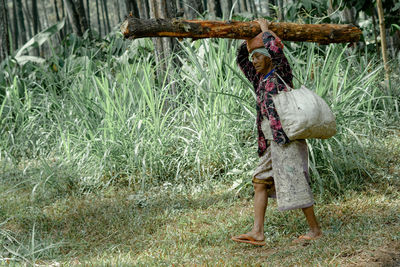 Man walking with log on grass