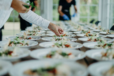 Midsection of man serving food in plates on table at wedding ceremony