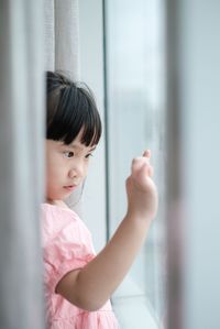 Portrait of cute girl looking through window