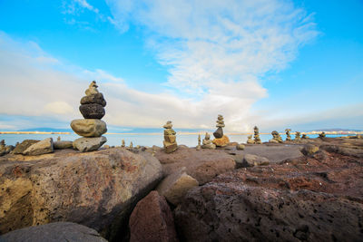 Rocks on beach against cloudy sky