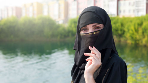 Portrait of a muslim woman in national dress in a city park against the background of a river