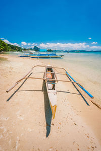 Deck chairs on shore at beach against sky