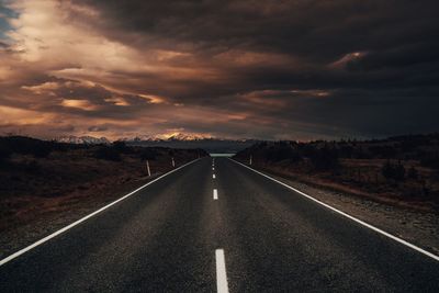 Empty road along landscape at sunset