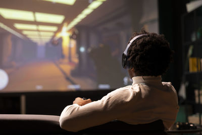 Rear view of shirtless man exercising in gym