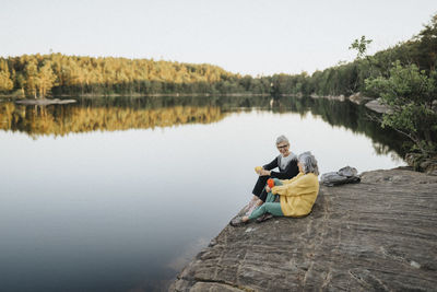 Two senior women sitting on rock at lakeshore