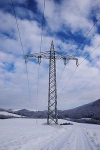 Electricity pylon against cloudy sky