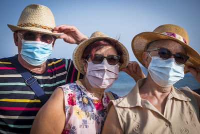 Portrait of senior people wearing sunglasses and mask standing outdoors