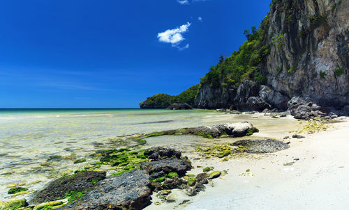 Scenic view of rocks on beach against blue sky