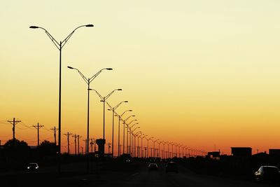 Silhouette of city street against clear sky during sunset