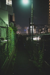 Illuminated street amidst buildings in city at night