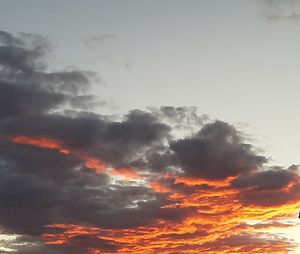 Low angle view of sunlight streaming through clouds during sunset