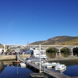 Boats moored in river against clear blue sky