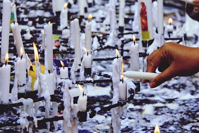 Cropped image of hand igniting candle