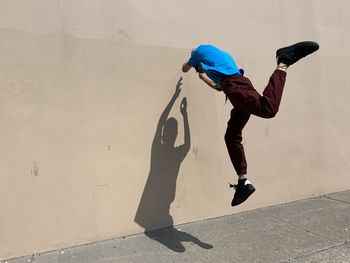 Full length of man jumping against wall