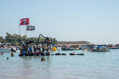 People on boats in sea against clear sky