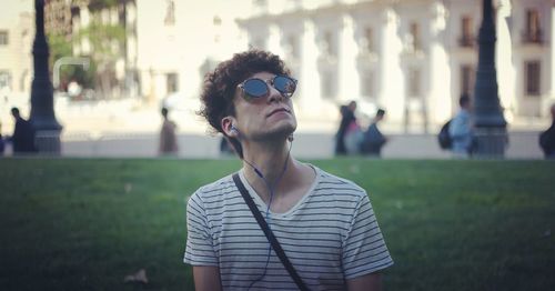 Close-up of young man wearing sunglasses and headphones while standing outdoors