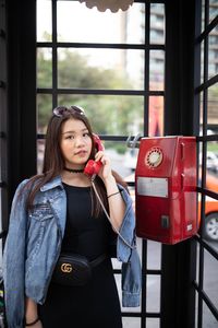 Portrait of woman making calling in telephone booth