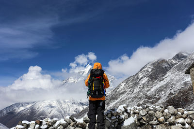 Rear view of hiker carrying backpack while standing on snow covered mountain