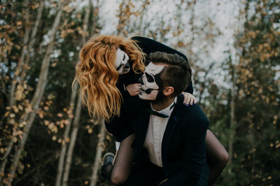 A couple in love is sitting hugging against the backdrop of mountains celebrating halloween in costu