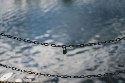 High angle view of padlock hanging on chain against river