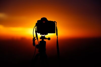 Silhouette of camera pointing towards sunset