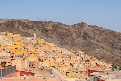 Aerial view of town by mountain against sky