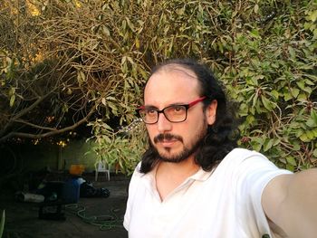 Thoughtful serious man looking away against trees at back yard