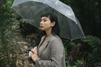 Young woman looking away while standing on rainy day
