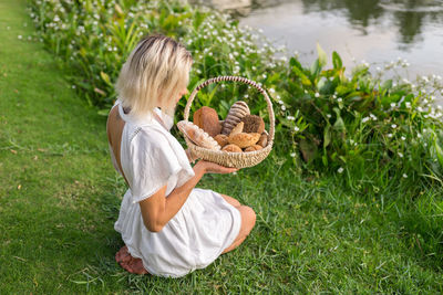 High angle view of woman with bread in basket on grass