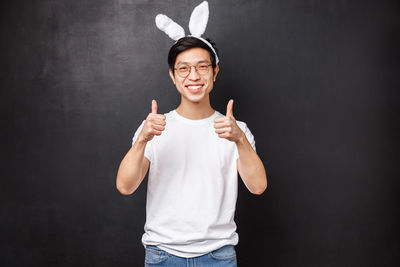 Portrait of smiling man gesturing while standing against black background