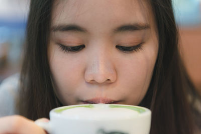 Close-up portrait of a serious young woman drinking water