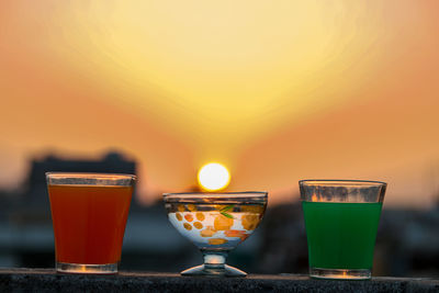 Close-up of wine glass on table against orange sky