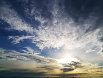 Low angle view of sunlight streaming through clouds