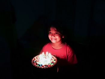 Girl looking at illuminated lamp in dark