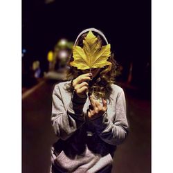 Midsection of man holding leaf at night