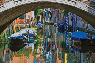 Boats moored in canal by buildings in city