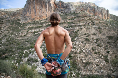 Rear view of shirtless muscular man looking at mountains