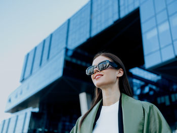 Portrait of young woman standing against buildings