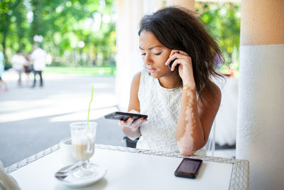 Young woman using mobile phone in cafe