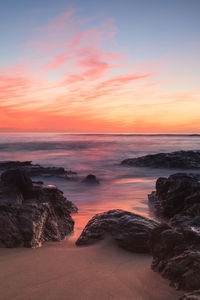 Scenic view of sea against cloudy sky during sunset