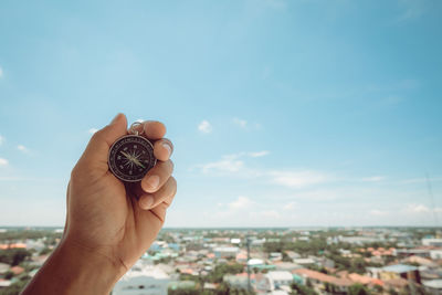 Midsection of person holding cityscape against sky