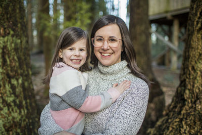 Young mother wearing glasses holds her cute daughter.