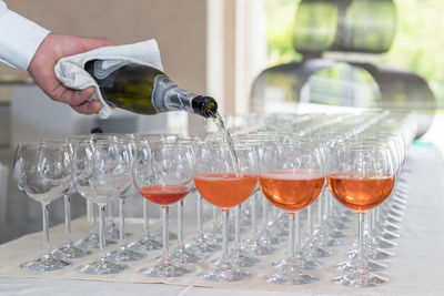 Close-up of hand pouring wine in glass bottle on table