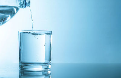 Close-up of drinking glass against blue background