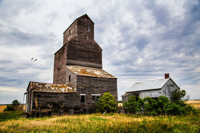 Old buildings on field against sky