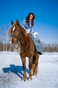 Man riding horse on snowy field against sky