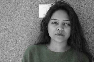 Close-up portrait of a young woman against wall