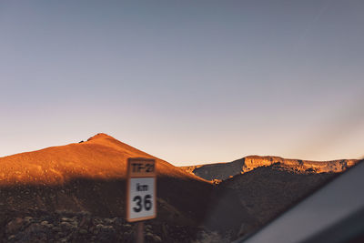 Information sign on mountain against clear sky